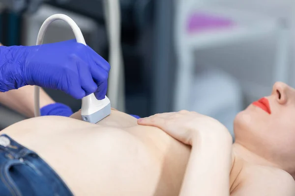 Una doctora que usa ultrasonido está examinando los senos de una paciente joven. Oficina de médicos. — Foto de Stock