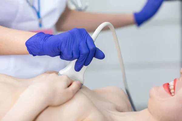 Una doctora que usa ultrasonido está examinando los senos de una paciente joven. Oficina de médicos. — Foto de Stock
