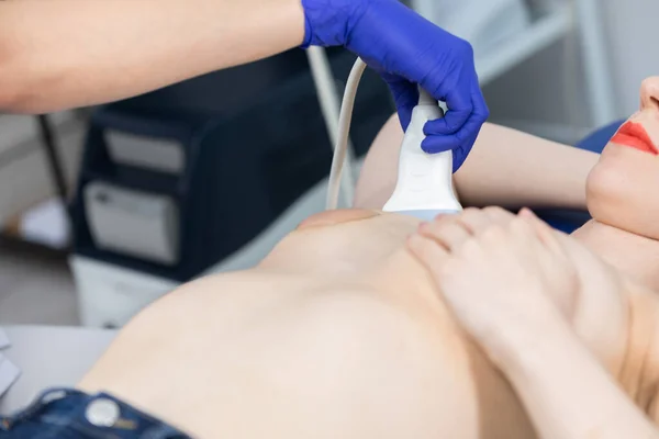 Un médico joven examina una mama de las pacientes con un ultrasonido. Prevención de la aparición del cáncer de mama. Vista de primer plano. — Foto de Stock
