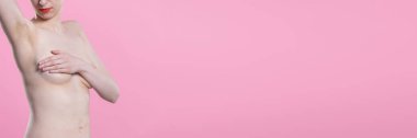 Bir eli havada genç ve çıplak bir kadın ve diğeri göğüslerini kapatıyor. Pembe arka planda bir portre. Panoramik çerçeve.