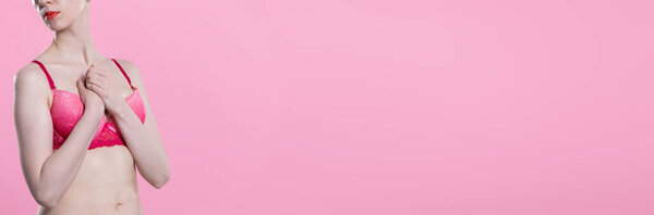 A woman in lingerie sensually hugs her hands to her chest as a sign of solidarity with the social fight against breast cancer. Panoramic frame.