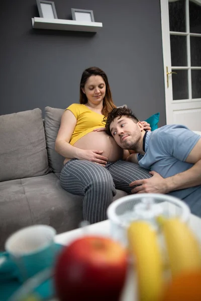 Ein Ehemann legt sein Ohr an den Bauch seiner schwangeren Frau, um ihr ungeborenes Kind zu fühlen und zu hören. Eine Frau in fortgeschrittener Schwangerschaft. — Stockfoto