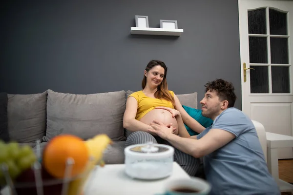 El marido abraza el vientre de las esposas embarazadas y se sonríen. Una mujer en embarazo avanzado. — Foto de Stock