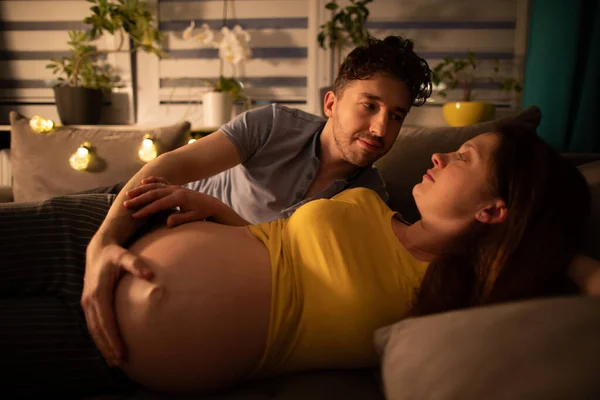 Ehepaar liegt im Bett und Ehemann umarmt schwangere Ehefrau Frau in fortgeschrittener Schwangerschaft. — Stockfoto