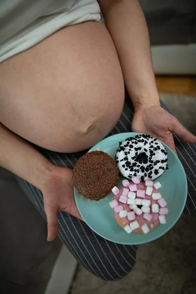 Vista aérea de una mujer de nueve meses de embarazo vientre y rosquillas dulces. Una mujer en embarazo avanzado. — Foto de Stock