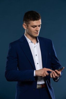 Yakışıklı bir adam cep telefonuyla numaralara basıyor. Takım elbise giymiş..