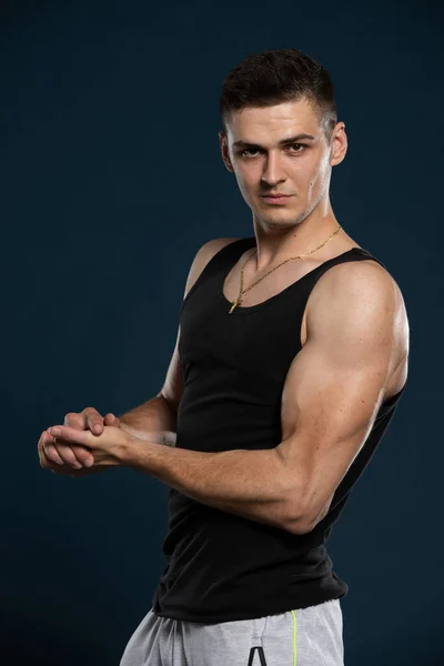 Ein Athlet außerhalb des Bodybuilding-Wassers zeigt seine Muskeln, indem er seine Armmuskeln anspannt. — Stockfoto