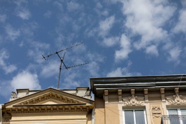 A stunning view of antennas on a historic building against a clear blue sky with soft, fluffy white clouds