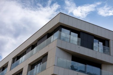 A contemporary building prominently showcasing sleek lines and impressive glass accents beneath a brilliant blue sky