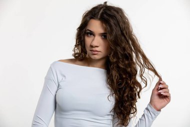 Büyüleyici bir portre, çarpıcı güzellikteki kıvırcık saçlı ve göz kamaştırıcı, modaya uygun bluzu olan bir kadın.