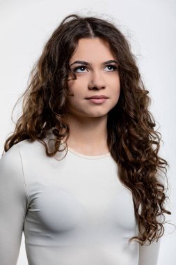 Bu büyüleyici bir portre. Çok güzel kıvırcık saçlı genç bir kadının minimalist bir arka planda sergilenmesi.