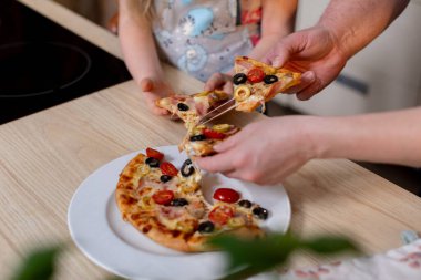 Neşeli ve neşeli bir aile anı. Lezzetli pizzaları birlikte paylaşıyorlar. Birlikte kalıcı anılar yaratıyorlar.