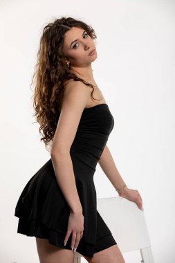 Şık bir kadın model zarif, siyah bir elbise içinde güzel bir şekilde zarafet ve özgüven göstererek poz verir.
