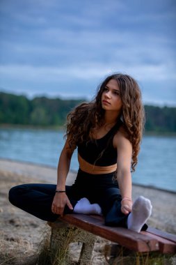 Gün batımında sakin bir gölün kenarına uzanan bir kadın içsel gücünü, zarafetini ve özgüvenini mükemmel bir şekilde sergiler.