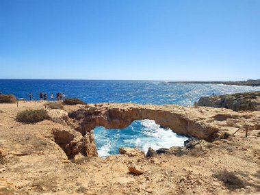 Çarpıcı bir doğal kaya kemeri. Canlı turkuaz suları var. Güneş ışığıyla güzelce aydınlatılıyor.