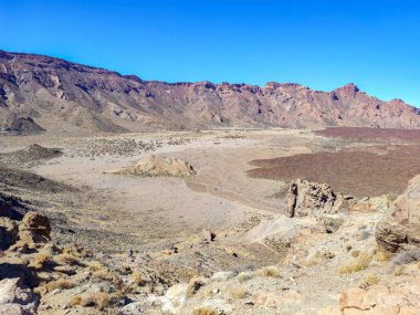 A stunning desert scene that beautifully showcases rugged mountains and arid terrain beneath a clear blue sky