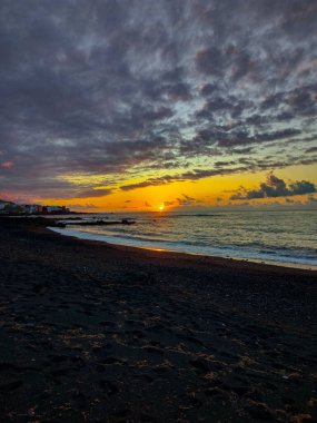 A breathtaking sunset casts beautiful warm colors over a tranquil, peaceful beach, creating a serene coastal scene