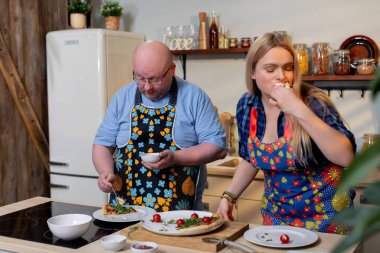 Yemek pişirme dersi atmosferi, erkek kadına mutfakta yemek yapma teknikleri gösterir, erkek öğretmen kadına taze sebzeleri mutlu bir şekilde hazırlama konusunda rehberlik eder.