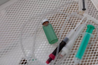 Tıbbi şırıngaların detaylı yakın plan görüntüsü yeşil bir şişenin yanında dikkatlice klinik tepsiye yerleştirilmiş.
