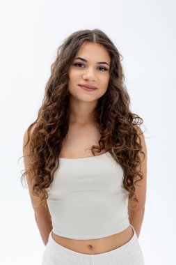 Stüdyo fotoğraflarındaki kendine güvenen kadın kıvırcık saçlı neşeli bir kadının portresi doğal stili ve arkadaş canlısı ifadesiyle rahatlamış bir kadının stüdyo fotoğrafı.