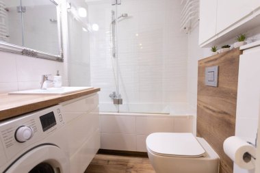 Bu şık ve modern banyo şık bir küvet, pratik çamaşır makinesi ve modern dekorla övünüyor.