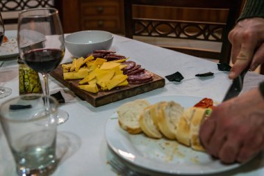 Tipik İtalyan aperatifleriyle dolu bir masa, sade ahşap bir masa üzerinde soğuk et ve bıçak. Kırmızı şaraplı bardaklar. Seçici odak.