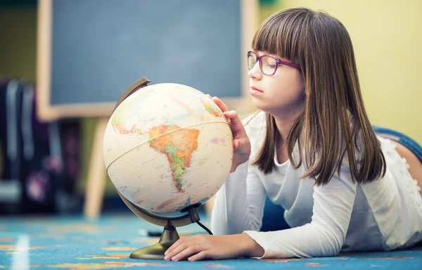 Pretty little student girl studying geography with globe in a child's room — Stok fotoğraf