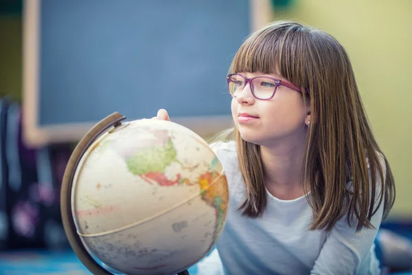 Menina estudante bonita estudando geografia com globo no quarto de uma criança — Fotografia de Stock