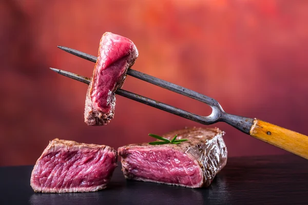 Carne de res asada. Porciones de carne de res gruesa filetes de solomillo jugosos en la parrilla de teflón o tablero de madera vieja — Foto de Stock