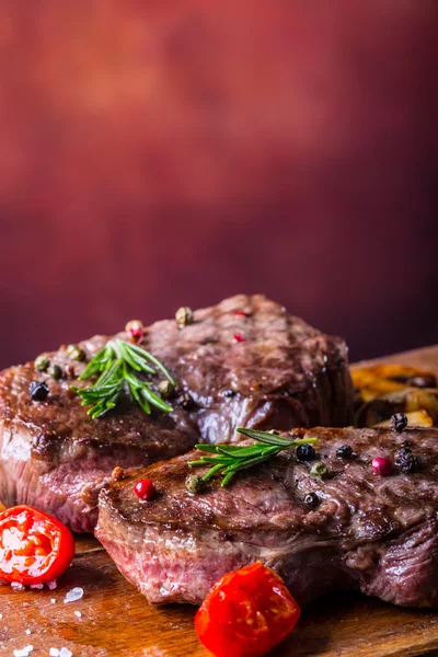 Bife grelhado. Porções de carne grossa bifes de lombo suculentos na grelha panela de teflon ou placa de madeira velha — Fotografia de Stock