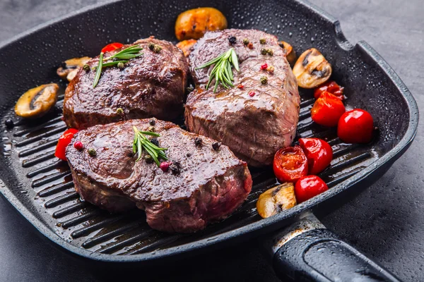 Bife grelhado. Porções de carne grossa bifes de lombo suculentos na grelha panela de teflon ou placa de madeira velha — Fotografia de Stock