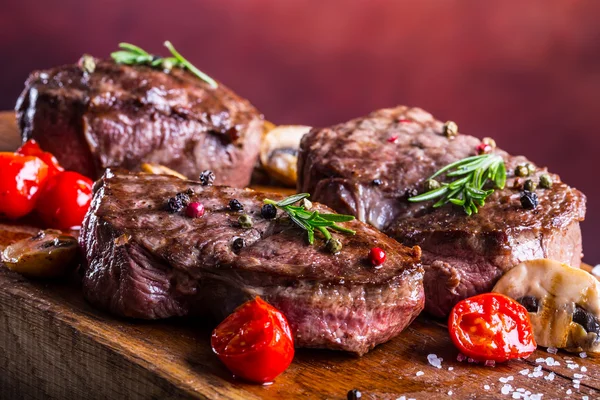 Bistecca di manzo alla griglia. Porzioni di carne di manzo succosa filetto bistecche sulla griglia teflon pan o vecchio bordo di legno — Foto Stock