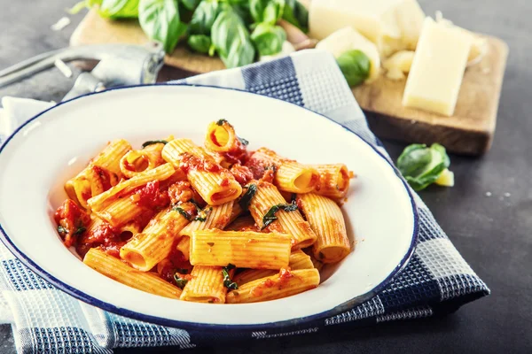 Pasta. Cocina italiana y mediterránea. Pasta Rigatoni con salsa de tomate hojas de albahaca ajo y queso parmesano. Una cocina casera antigua con utensilios de cocina antiguos —  Fotos de Stock