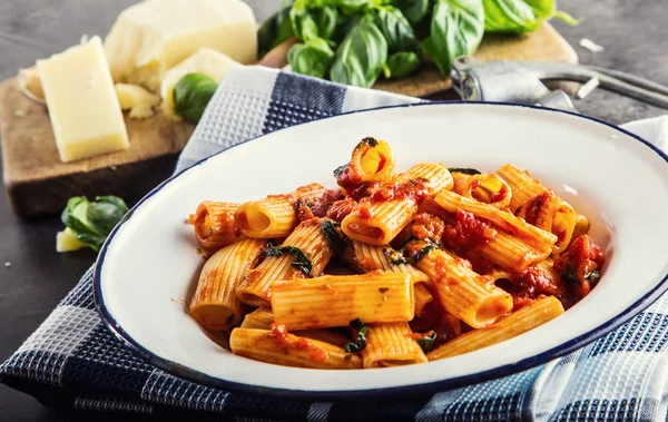 Pasta. Cocina italiana y mediterránea. Pasta Rigatoni con salsa de tomate hojas de albahaca ajo y queso parmesano. Una cocina casera antigua con utensilios de cocina antiguos —  Fotos de Stock