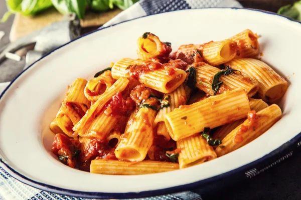 Pasta. Cocina italiana y mediterránea. Pasta Rigatoni con salsa de tomate hojas de albahaca ajo y queso parmesano. Una cocina casera antigua con utensilios de cocina antiguos —  Fotos de Stock