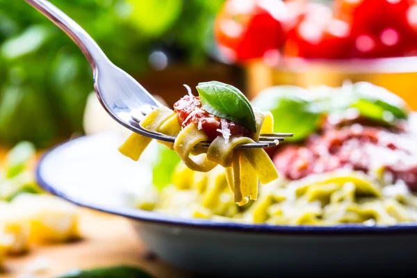 Paste. Bucătărie italiană și mediteraneană. Paste Fettuccine cu sos de roșii busuioc frunze usturoi și brânză parmezan. O bucătărie veche cu ustensile de bucătărie vechi. Porție de pe o furculiță paste cu sos de roșii și frunze de busuioc — Fotografie, imagine de stoc