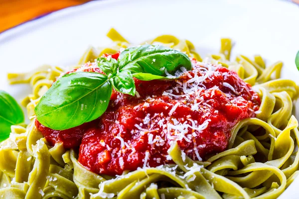 Pasta. Cocina italiana y mediterránea. Pasta Fettuccine con salsa de tomate hojas de albahaca ajo y queso parmesano. Una antigua cocina casera con utensilios de cocina antiguos. Porción de en un tenedor pasta con salsa de tomate y hojas de albahaca — Foto de Stock