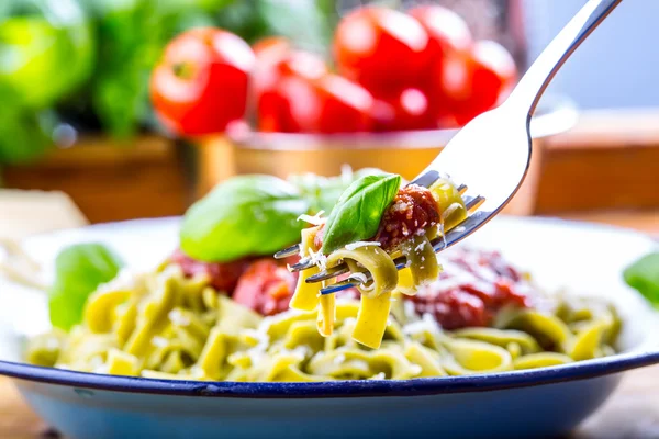 Pasta. Cocina italiana y mediterránea. Pasta Fettuccine con salsa de tomate hojas de albahaca ajo y queso parmesano. Una antigua cocina casera con utensilios de cocina antiguos. Porción de en un tenedor pasta con salsa de tomate y hojas de albahaca — Foto de Stock