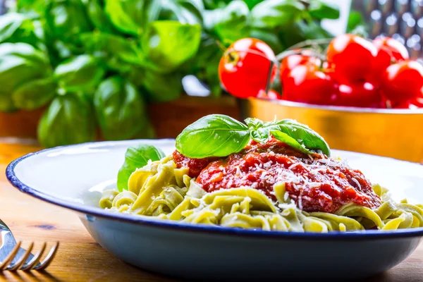 Pasta. Cocina italiana y mediterránea. Pasta Fettuccine con salsa de tomate hojas de albahaca ajo y queso parmesano. Una antigua cocina casera con utensilios de cocina antiguos. Porción de en un tenedor pasta con salsa de tomate y hojas de albahaca — Foto de Stock