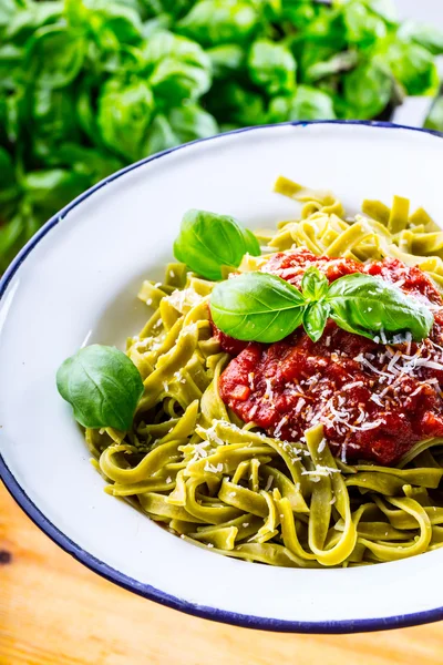 Pasta. Cocina italiana y mediterránea. Pasta Fettuccine con salsa de tomate hojas de albahaca ajo y queso parmesano. Una antigua cocina casera con utensilios de cocina antiguos. Porción de en un tenedor pasta con salsa de tomate y hojas de albahaca — Foto de Stock