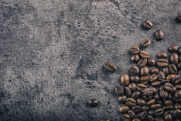 Du café. grains de café torréfiés déversés librement sur un fond de béton — Photo