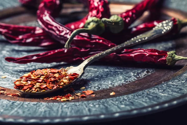 Chili. Chili peppers. Several dried chilli peppers and crushed peppers on an old spoon spilled around. Mexican ingredients - cuisine