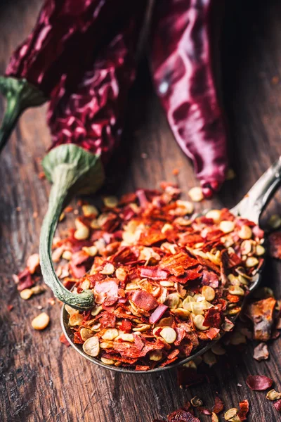 Chili. Chili peppers. Several dried chilli peppers and crushed peppers on an old spoon spilled around. Mexican ingredients - cuisine