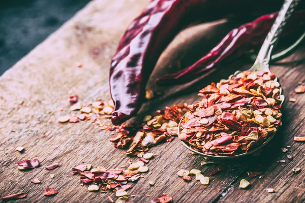 Chili. Chili paprika. Több szárított chili paprika, és összetörni paprika egy régi kanalat, ezen a környéken: kiömlött. Mexikói Hozzávalók - konyha — Stock Fotó