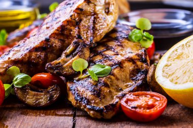 Çeri domatesli, mantarlı, otlu farklı çeşitlerde ızgara tavuk göğsü, ahşap bir tahtada limon kesimi veya teflon tavası. Geleneksel mutfak. Izgara mutfağı