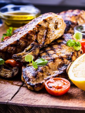 Çeri domatesli, mantarlı, otlu farklı çeşitlerde ızgara tavuk göğsü, ahşap bir tahtada limon kesimi veya teflon tavası. Geleneksel mutfak. Izgara mutfağı