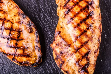 Çeri domatesli, mantarlı, otlu farklı çeşitlerde ızgara tavuk göğsü, ahşap bir tahtada limon kesimi veya teflon tavası. Geleneksel mutfak. Izgara mutfağı