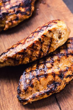 Çeri domatesli, mantarlı, otlu farklı çeşitlerde ızgara tavuk göğsü, ahşap bir tahtada limon kesimi veya teflon tavası. Geleneksel mutfak. Izgara mutfağı