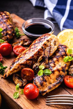 Çeri domatesli, mantarlı, otlu farklı çeşitlerde ızgara tavuk göğsü, ahşap bir tahtada limon kesimi veya teflon tavası. Geleneksel mutfak. Izgara mutfağı