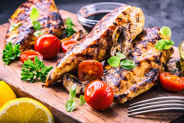 Grilled chicken breast in different variations with cherry tomatoes,  mushrooms, herbs, cut lemon on a wooden board or teflon pan. Traditional cuisine. Grill kitchen — Stock Photo, Image